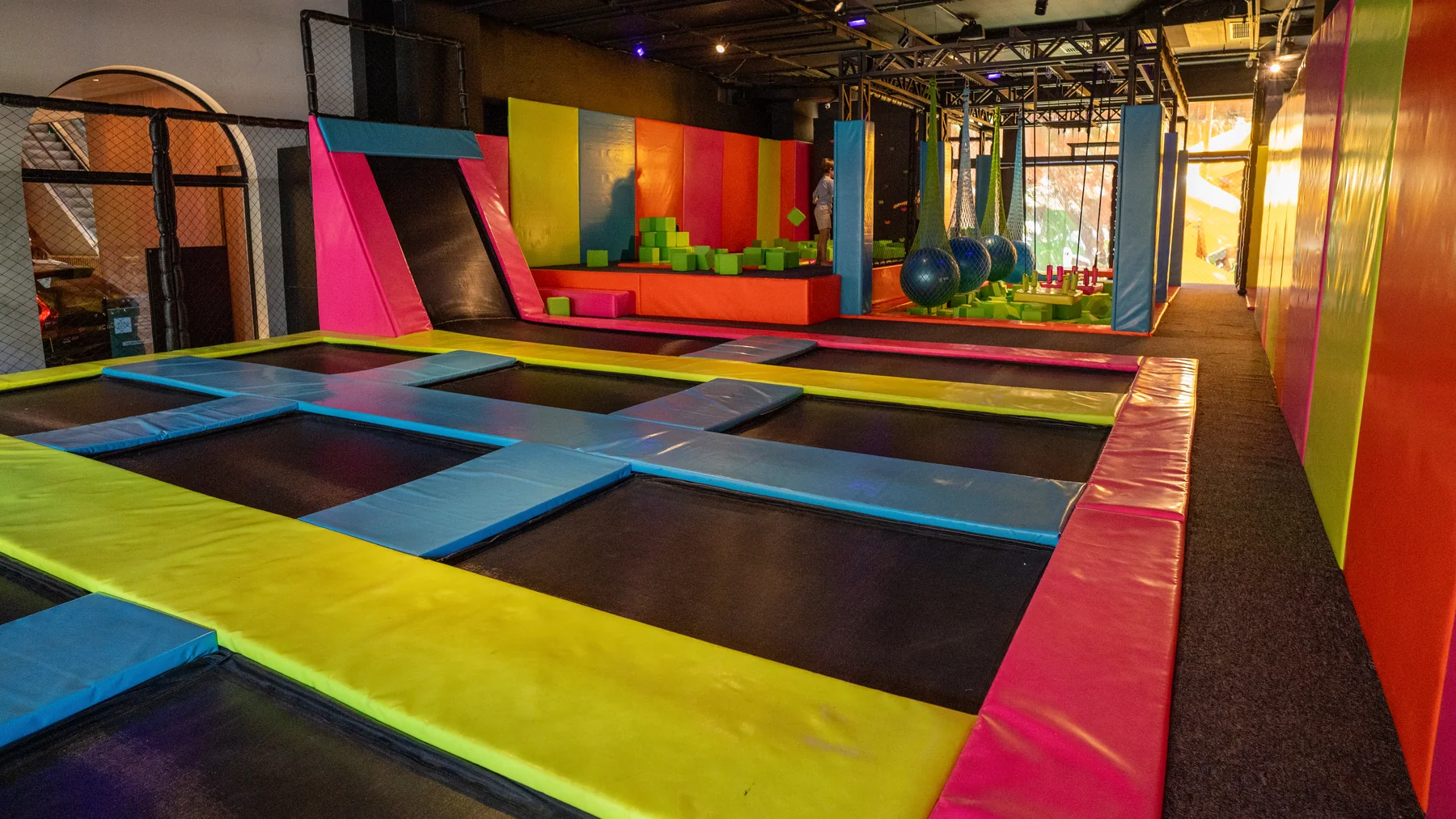 Área interna com trampolins, cores vibrantes e equipamentos de recreação